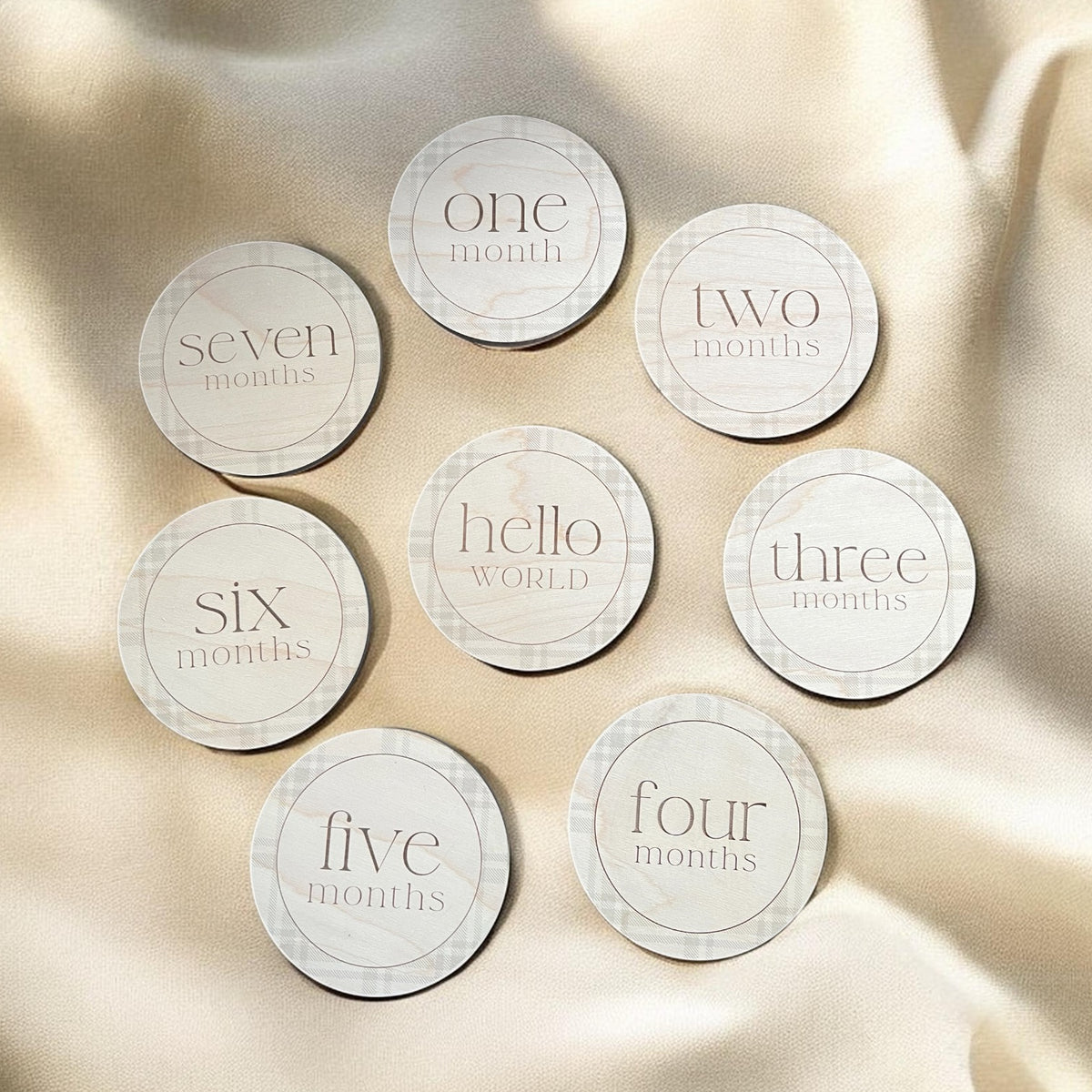 Engraved wooden baby milestone markers with plaid border, featuring Hello World and monthly milestone discs