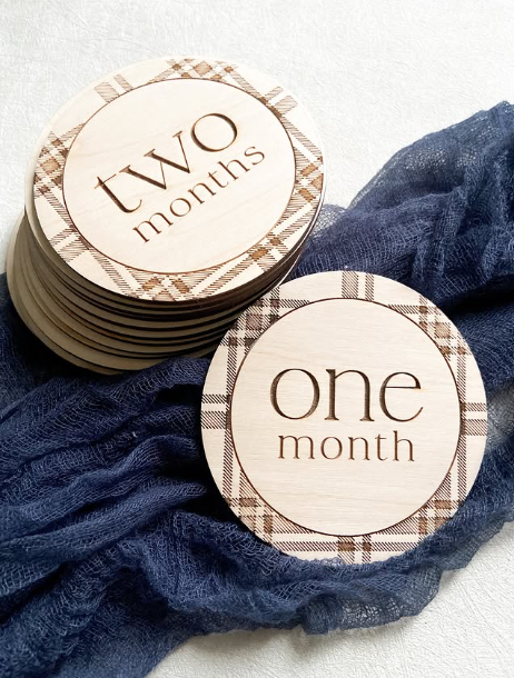 Engraved maple Baby's First Year milestone discs with plaid border showing one month and two months